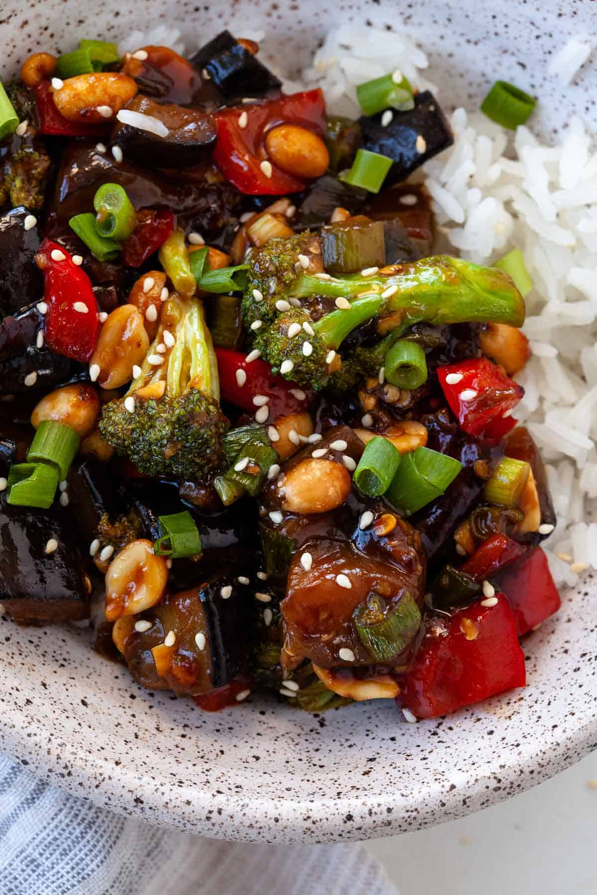 kung pao vegetables with rice in white speckled bowl on white marble counter